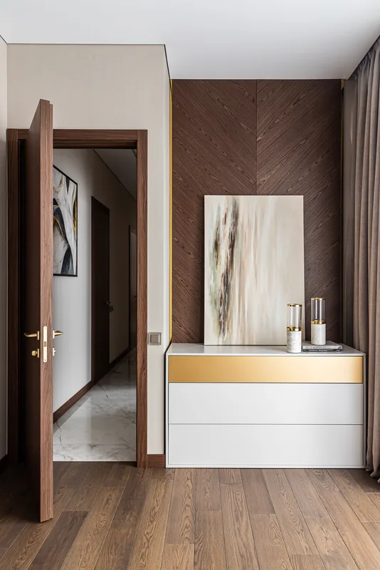 Chest of drawers with brass insert beside the herringbone wall panel